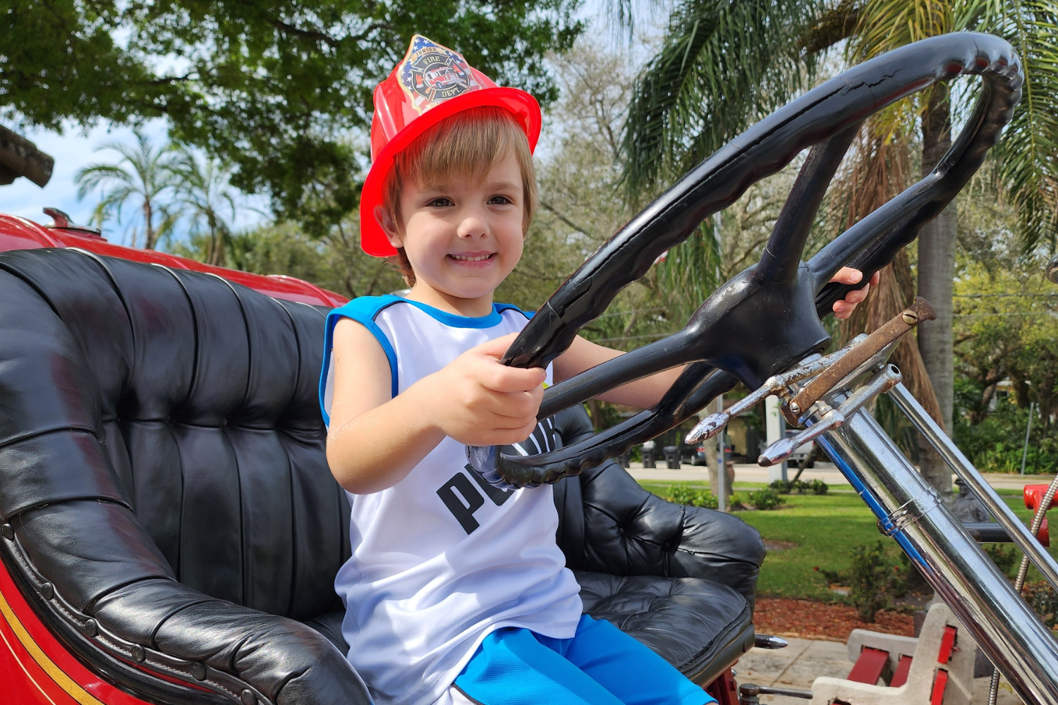Child learning about fire safety beside a vintage fire truck at the Fort Lauderdale Fire and Safety Museum.