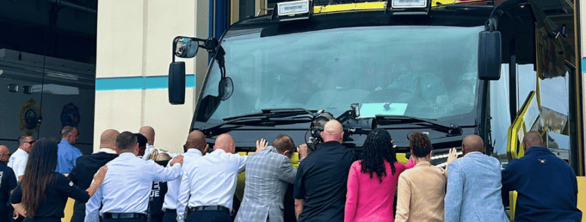 Fort Lauderdale Fire Rescue team and city officials standing in front of new Hazmat and ARFF fire trucks during fire truck push-in ceremony
